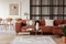 Stylish brown corner sofa with patterned pillows in elegant living room interior with mullions wall