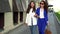 Stylish brunette women are walking together on city street at daytime, friends or colleagues are chatting