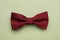 Stylish burgundy bow tie with polka dot pattern on pale green background, top view