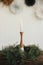 Stylish burning candle in rustic christmas wreath on wooden table on background of paper swedish stars on wall. Christmas advent.