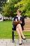 Stylish business woman siting on park bench writing in notebook