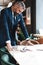 Stylish businessman standing near table in the office and reading documents