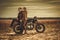 Stylish cafe racer couple on the vintage custom motorcycles in a field.