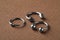 Stylish captive bead and horseshoe rings on brown background, closeup. Piercing jewelry