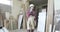 A stylish carpenter in the joinery uniform and a white helmet talking on the mobile phone at a furniture factory.