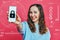 Stylish caucasian girl in a pale blue t-shirt on a pink background. Hand holds smartphone with padlock icon. Security concept