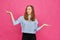 Stylish caucasian girl in a pale blue t-shirt shows hands abstract scales on a pink background