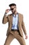 Stylish caucasian man in brown suit with open collar shirt fixing sunglasses