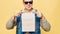 Stylish Caucasian man in a jeans and sunglasses on a yellow background. The concept of a call to learning and speaking English