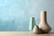 Stylish ceramic vases on wooden table against light blue background. Space for text