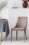 Stylish chair next to dining table with grey tablecloth in trendy dining room interior