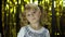 Stylish child dancing fooling around, make faces. Girl posing on background with foil golden curtain