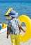 Stylish child wearing colorful clothes and holding yellow float at beach