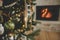 Stylish christmas baubles on tree close up against burning fireplace. Beautiful decorated christmas tree with vintage baubles and