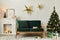 Stylish christmas living room interior with green sofa, white chimney, christmas tree and wreath, stars, gifts and decoration.