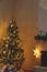 Stylish christmas living room with modern decorated christmas tree and festive decor on fireplace mantel with golden light.