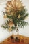 Stylish christmas star straw ornaments and paper angel on pine branches on table in vase on background sweden star. Festive