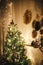 Stylish Christmas tree decorated with modern white baubles, boho ornaments and golden lights on background of paper stars on wall