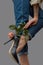 Stylish composition of beautiful female legs in jeans, black high heeled shoes and a pink rose adorning the leg around a