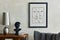 Stylish composition of creative living room interior with mock up poster frame, lamp and sculpture on the wooden commode, grey.