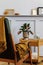 Stylish composition at living room interior with design armchair, plaid, clock, plant, air plant, book, wood panels with shelf.
