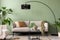 The stylish composition at living room interior with green wall, design gray sofa, coffee table, armchair and elegant personal