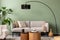 The stylish composition at living room interior with green wall, design gray sofa, wooden coffee table, armchair and elegant