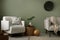 Stylish composition of living room interior with green wall, grey sofa with pillow. White armchair with brown pilow, wooden coffe