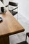 Stylish composition of wooden craft table with design black chairs, mug, book and concrete floor.