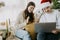 Stylish couple with cute white dog in lights and santa hat celebrating christmas holidays at home