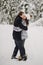 Stylish couple in love gently kissing in snowy mountains. Portraits of happy family gently embracing and smiling in winter