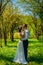 Stylish couple in love portrait, Newlywed husband and wife in circlet of flowers hugging near tree outdoors, summer nature concept