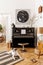 Stylish and cozy interior of living room with black piano, furniture, plant, wooden clock, lamp, mock up painitngs, decoration.