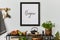 Stylish and cozy kitchen interior composition with mock up poster frame, black console, teapot, plants and retro inspired.