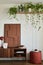 Stylish and creative living room interior design with wooden commode, structure painting, plants and personal decorations. Sunny.