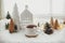 Stylish cup of tea with modern christmas houses, pine cone, wooden star and tree decor, golden lights on warm blanket on