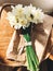 Stylish daffodils on rustic wooden chair in sunny light. Fresh yellow flowers bouquet on chair, countryside still life. Hello