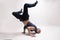 Stylish dancer doing breakdance figures. Standing on both hands, head down and both legs up