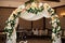 stylish decorated arch with flowers at the reception in a restaurant for a wedding