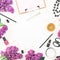 Stylish desktop with woman cosmetics, accessories, bijouterie and branches of pink lilac on white background. Flat lay, top view.