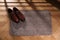 Stylish door mat with shoes on floor indoors, above view