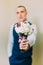 Stylish dressed man holding elegant bouquet indoor. Focus on flowers with blurred person image