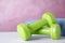 Stylish dumbbells and towel on table against color background. Home fitness