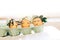Stylish Easter eggs with cute faces in floral wreath crowns in carton tray on rustic background. Modern easter eggs with flowers