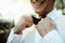 Stylish elegant groom tying classic bowtie and smiling in the sunny woods