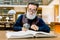 Stylish elegant senior man sits in vintage interior in library, holds magnifying glass and reads book. Bearded man in