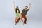 Stylish emotional young man and woman in fashionable retro outfits dancing disco dance isolated over grey studio