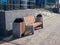 Stylish ensemble of a bench and trash bins made of stone and wood near a business building