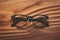 Stylish eyeglasses with black frames set against natural wooden background