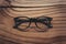 Stylish eyeglasses with black frames set against natural wooden background